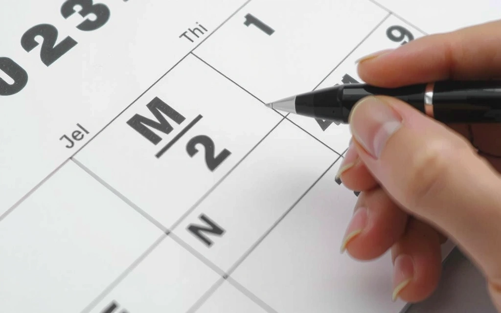 Osoba przekreślająca datę w kalendarzu, symbolizująca anulowanie